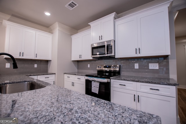 kitchen featuring decorative backsplash, stainless steel appliances, sink, stone counters, and white cabinetry