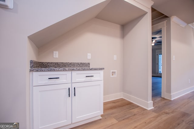 interior space with lofted ceiling, white cabinetry, light wood-type flooring, and stone countertops