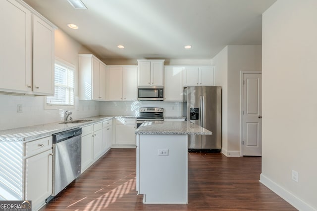 kitchen with white cabinets, stainless steel appliances, sink, and a kitchen island