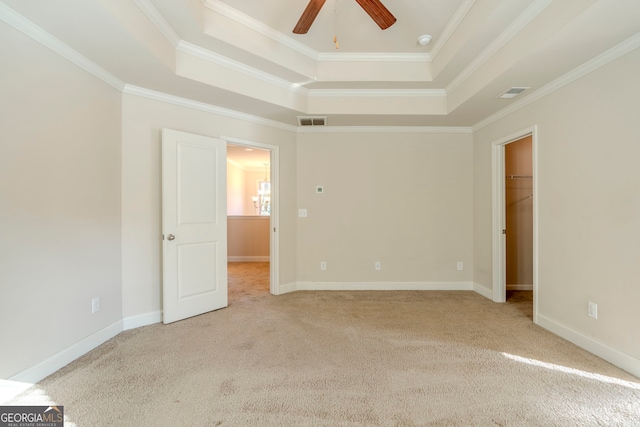 empty room featuring a raised ceiling, ceiling fan, and crown molding