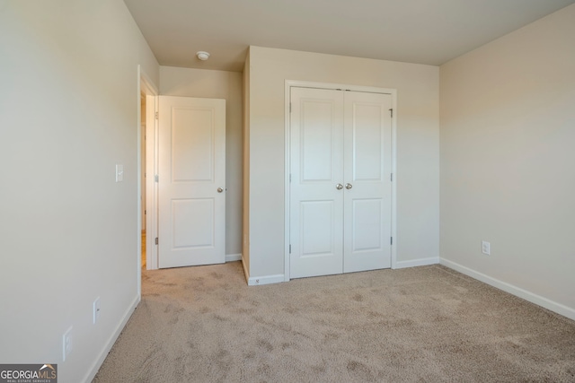 unfurnished bedroom with a closet and light colored carpet