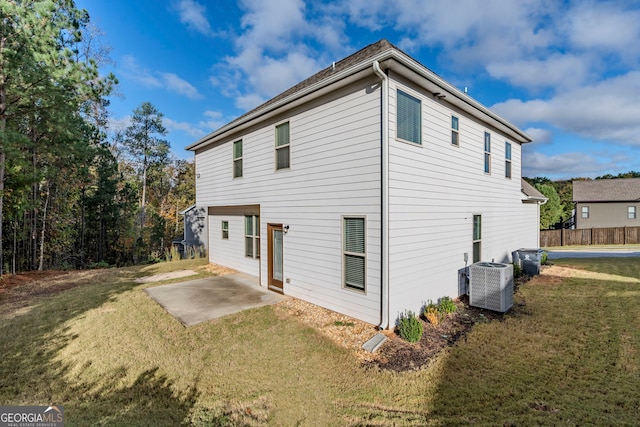 rear view of property with a patio, central AC unit, and a yard