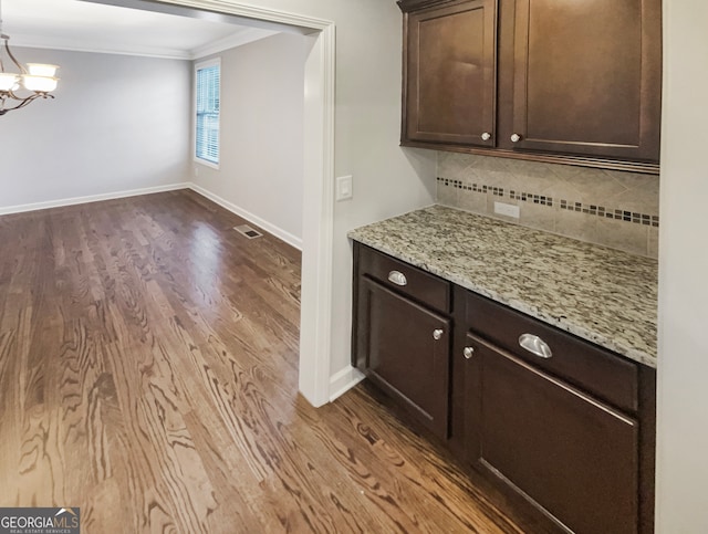 bar with wood-type flooring, backsplash, light stone counters, and crown molding