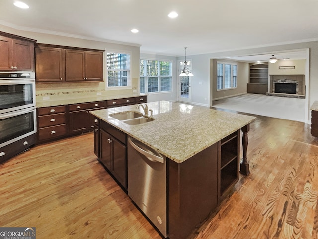 kitchen featuring light hardwood / wood-style flooring, an island with sink, crown molding, and stainless steel appliances