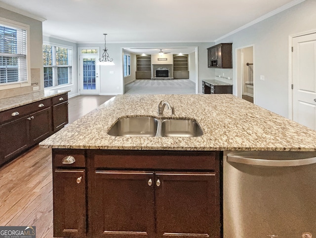 kitchen with a center island with sink, ornamental molding, sink, and light wood-type flooring