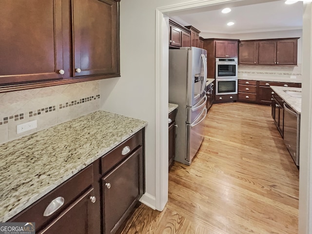 kitchen featuring light hardwood / wood-style flooring, backsplash, stainless steel appliances, and light stone counters