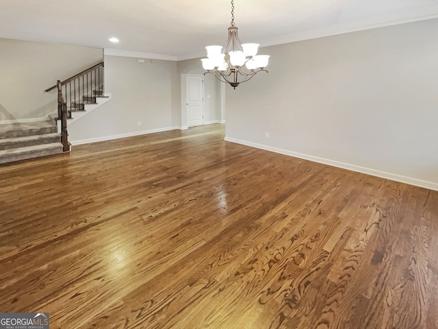 unfurnished dining area featuring hardwood / wood-style floors, a chandelier, and crown molding