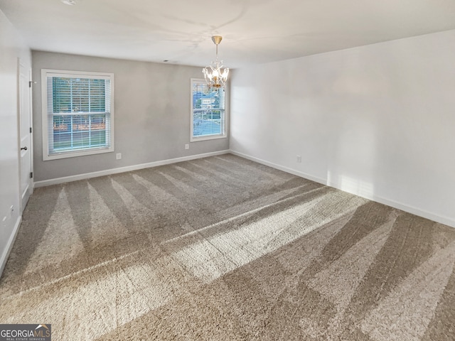 spare room featuring carpet flooring, plenty of natural light, and a notable chandelier