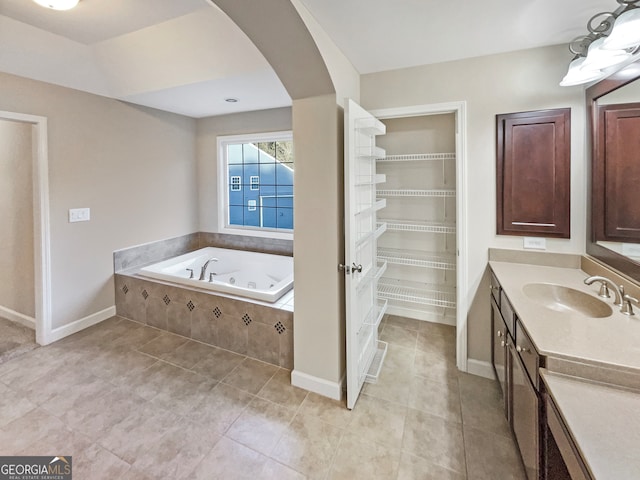 bathroom with vanity, tile patterned flooring, and a relaxing tiled tub