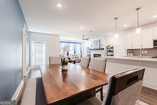 dining space featuring dark hardwood / wood-style flooring, ceiling fan, and sink