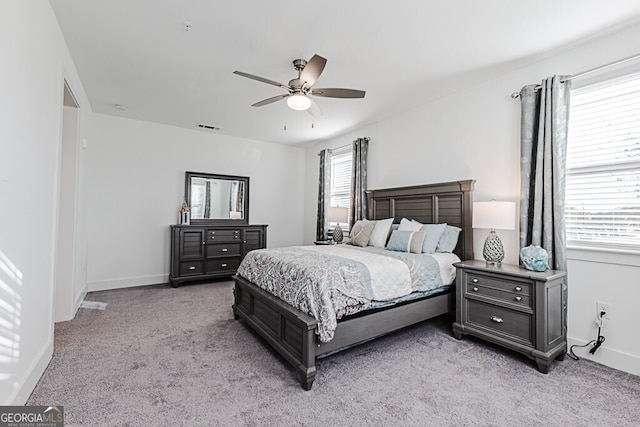 bedroom with light colored carpet, multiple windows, and ceiling fan