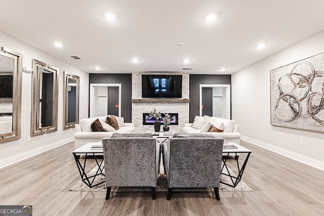 living room featuring a stone fireplace and light wood-type flooring