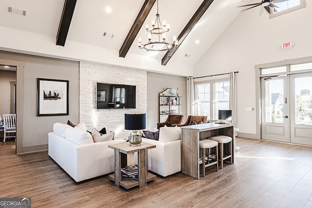 living room featuring french doors, ceiling fan with notable chandelier, beam ceiling, high vaulted ceiling, and hardwood / wood-style floors