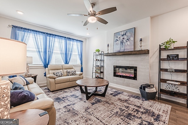 living room with a tile fireplace, hardwood / wood-style flooring, and ceiling fan