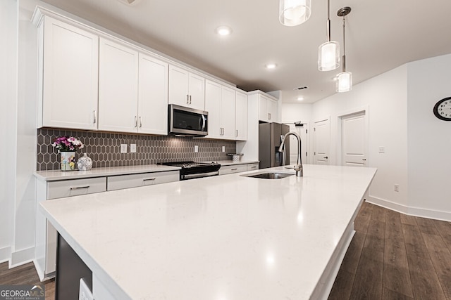 kitchen with white cabinetry, a kitchen island with sink, hanging light fixtures, and appliances with stainless steel finishes