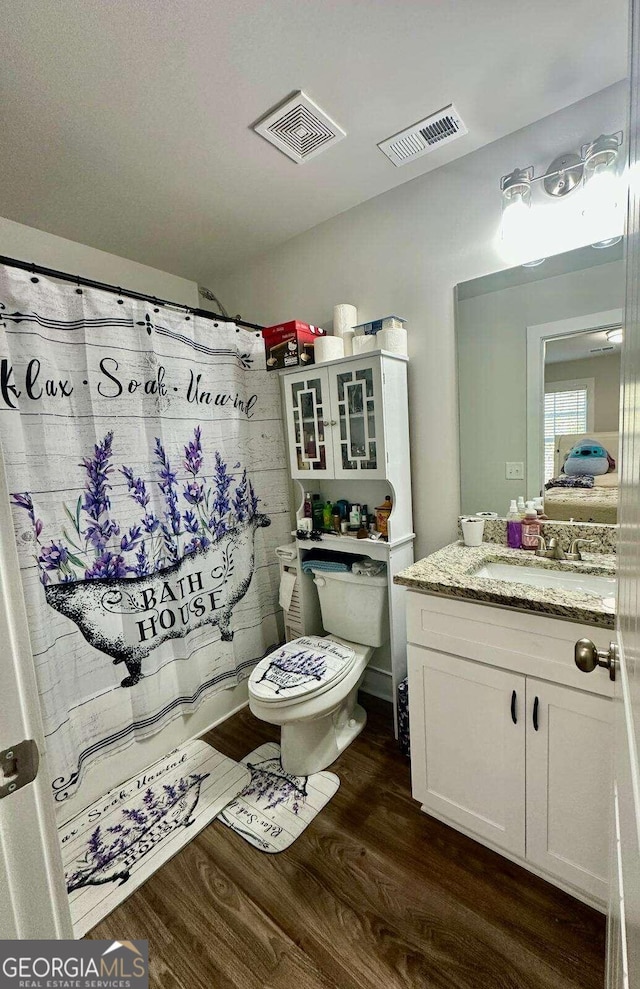 bathroom with toilet, hardwood / wood-style flooring, and vanity