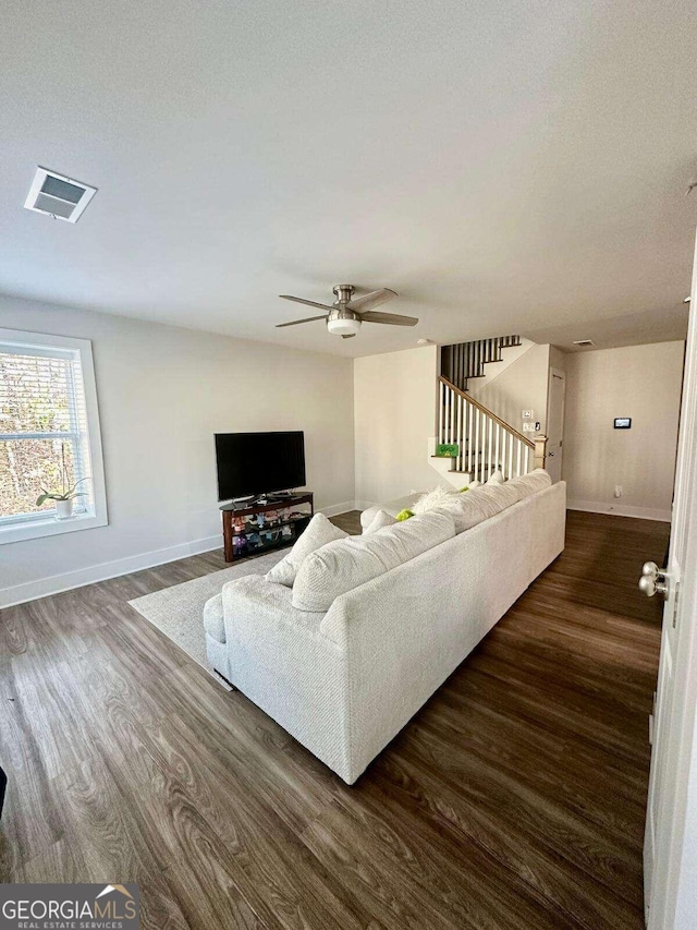 living room featuring ceiling fan and dark hardwood / wood-style flooring