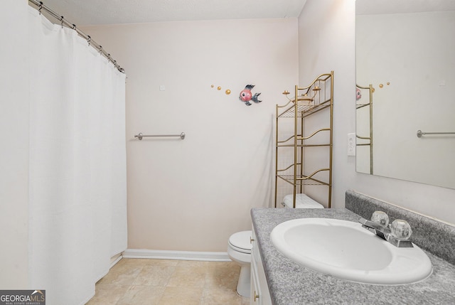 bathroom with baseboards, vanity, and toilet