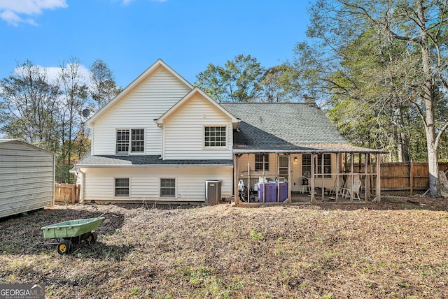 rear view of house with roof with shingles, fence, an outdoor structure, a patio area, and a shed