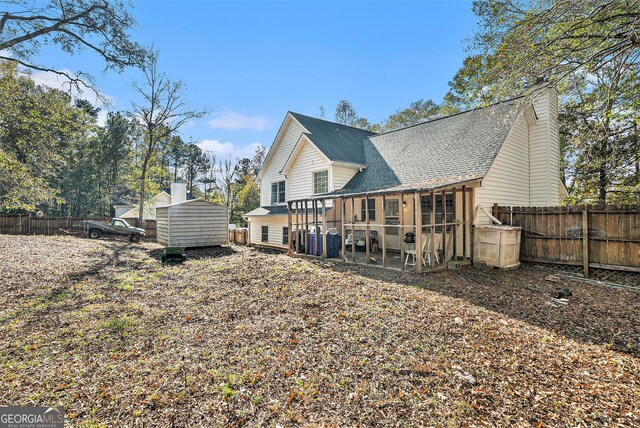 back of property with a fenced backyard, a chimney, a shingled roof, and an outbuilding