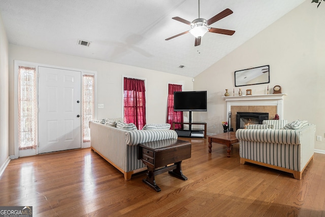 living area featuring lofted ceiling, plenty of natural light, wood finished floors, and visible vents