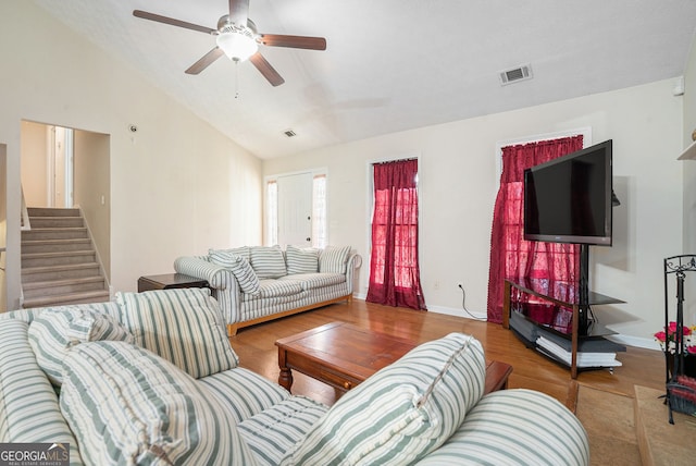 living area with visible vents, stairway, a ceiling fan, vaulted ceiling, and wood finished floors