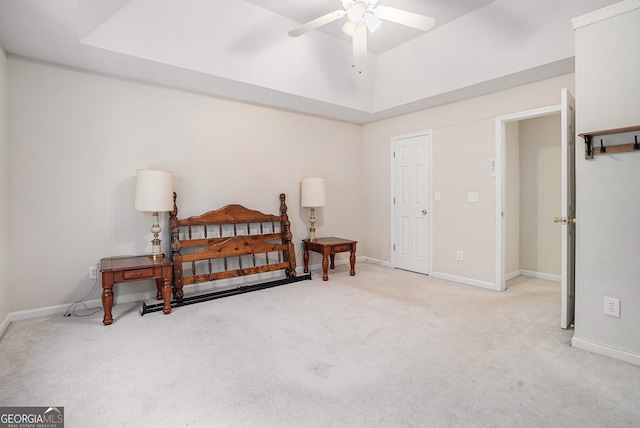 carpeted bedroom with ceiling fan, baseboards, and a raised ceiling