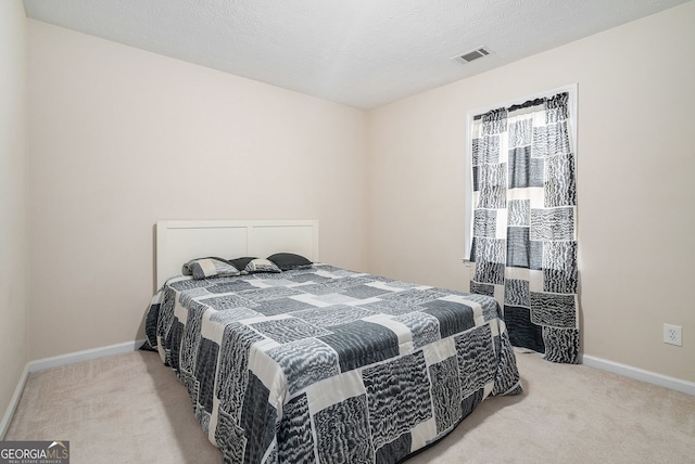 carpeted bedroom featuring baseboards, visible vents, and a textured ceiling