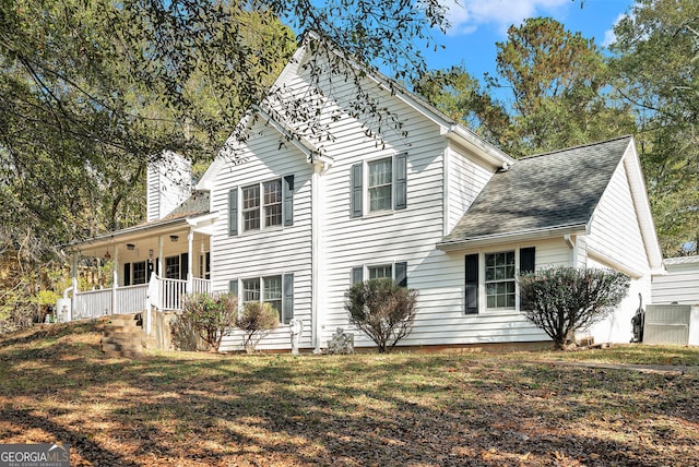 view of front of home featuring a chimney, a shingled roof, covered porch, a garage, and a front lawn