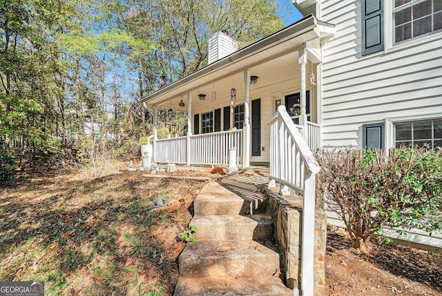 doorway to property featuring a chimney and a porch