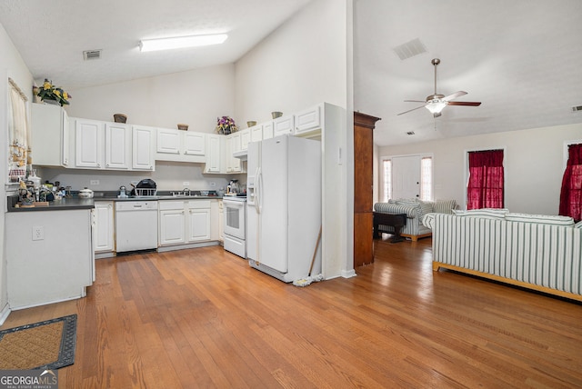 kitchen with dark countertops, white appliances, white cabinetry, and visible vents