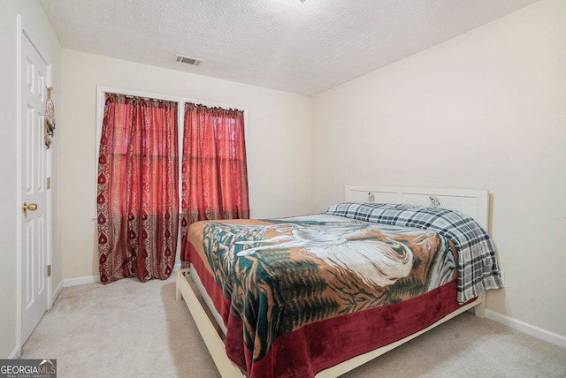 carpeted bedroom featuring visible vents, baseboards, and a textured ceiling