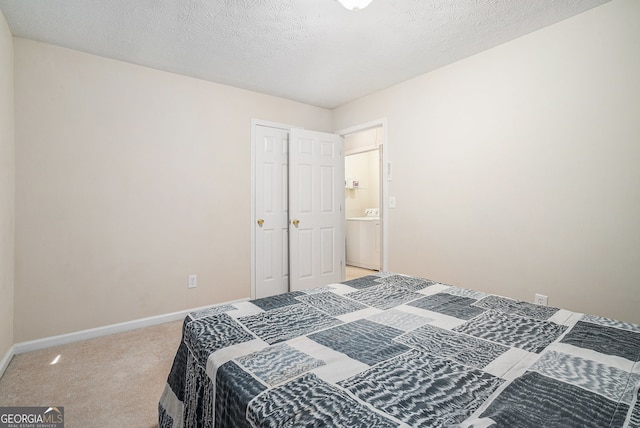 bedroom featuring carpet floors, baseboards, washer / clothes dryer, and a textured ceiling