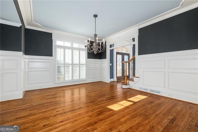 unfurnished dining area with hardwood / wood-style floors, a notable chandelier, and crown molding