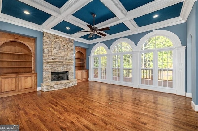 unfurnished living room featuring coffered ceiling, ceiling fan, crown molding, wood-type flooring, and a fireplace