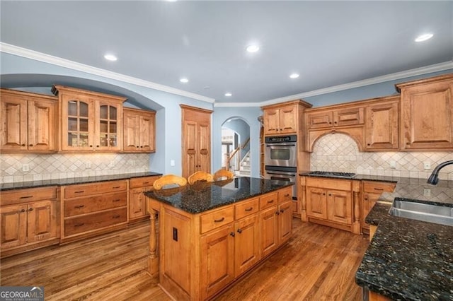 kitchen with decorative backsplash, stainless steel appliances, sink, hardwood / wood-style flooring, and a center island