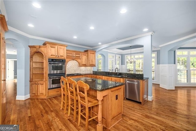 kitchen featuring ornamental molding, hardwood / wood-style flooring, a center island, and appliances with stainless steel finishes