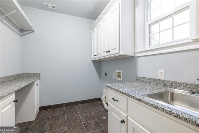 laundry area with hookup for an electric dryer, hookup for a washing machine, and cabinets