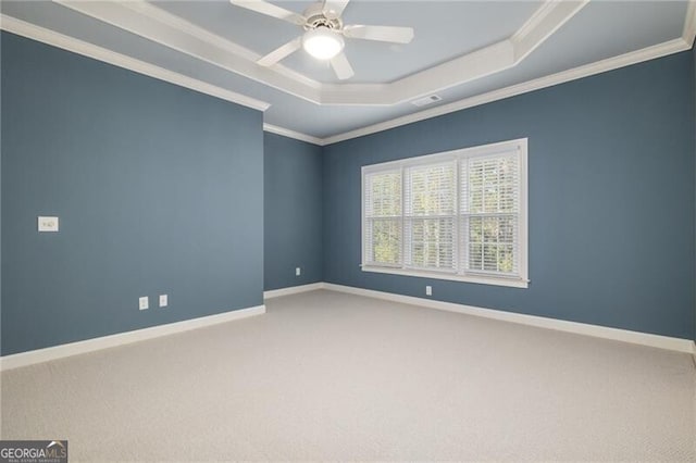 carpeted spare room with ceiling fan, crown molding, and a tray ceiling