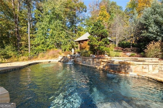 view of swimming pool with a jacuzzi, pool water feature, and a water view