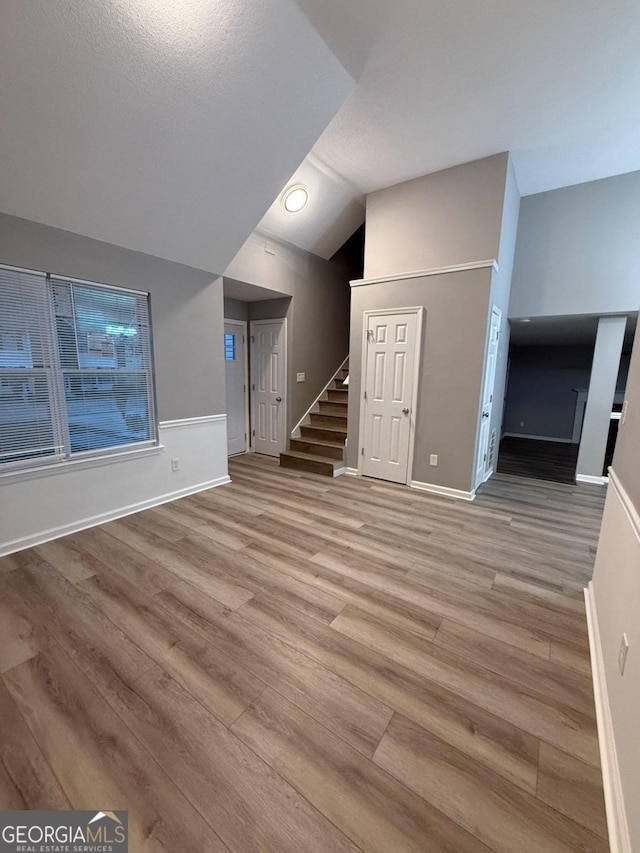 unfurnished living room featuring lofted ceiling and light hardwood / wood-style floors