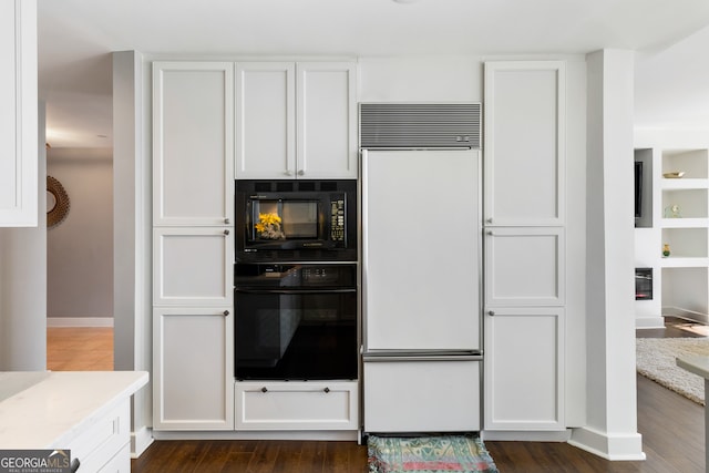 kitchen with black appliances, dark hardwood / wood-style floors, and white cabinets