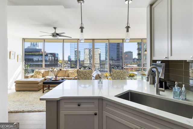 kitchen with decorative backsplash, sink, decorative light fixtures, hardwood / wood-style floors, and gray cabinets