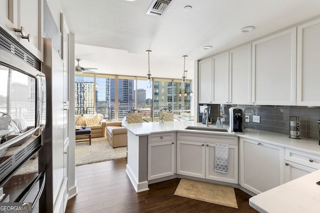 kitchen with a wealth of natural light, sink, dark hardwood / wood-style floors, pendant lighting, and white cabinets