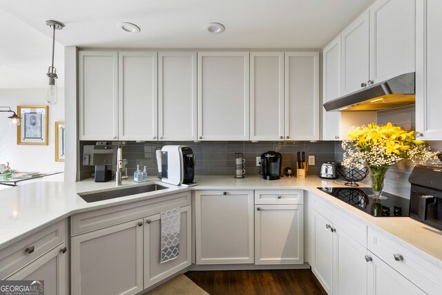 kitchen featuring black electric stovetop, dark hardwood / wood-style flooring, sink, white cabinetry, and hanging light fixtures