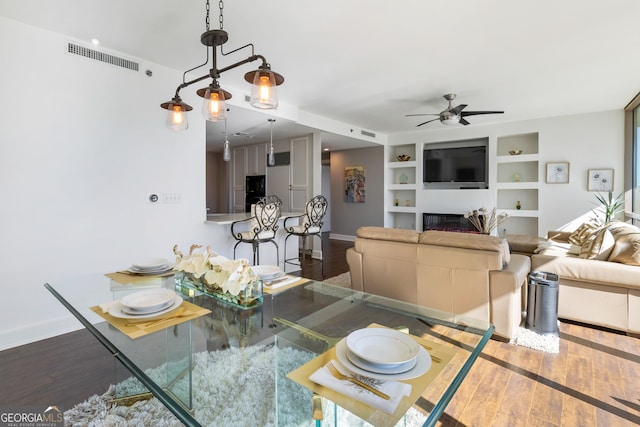 dining area featuring built in shelves, ceiling fan, and dark hardwood / wood-style flooring