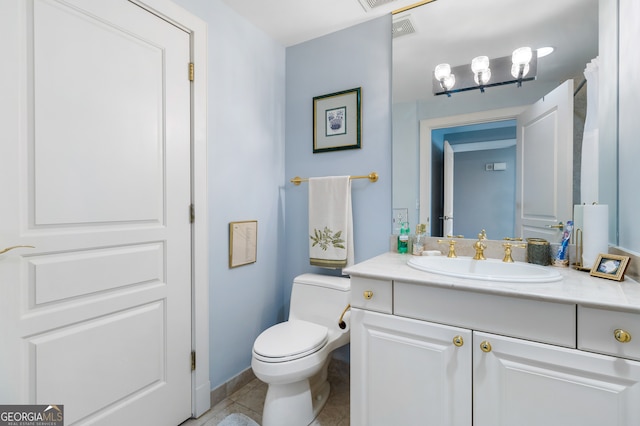 bathroom with toilet, vanity, and tile patterned floors