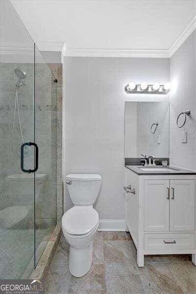 bathroom with vanity, an enclosed shower, toilet, and crown molding