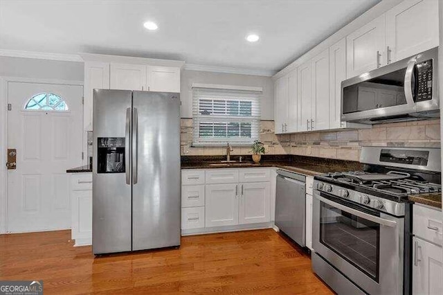 kitchen with white cabinets, appliances with stainless steel finishes, a healthy amount of sunlight, and light hardwood / wood-style floors