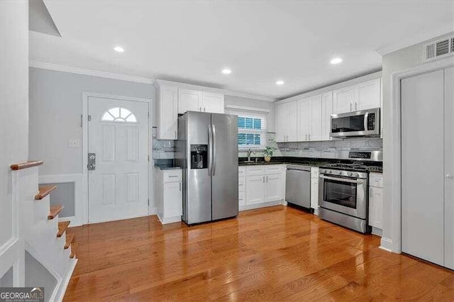 kitchen with white cabinetry, sink, tasteful backsplash, light hardwood / wood-style flooring, and appliances with stainless steel finishes